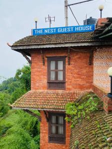 ein Backsteinhaus mit einem Schild darüber in der Unterkunft The Nest Guest House in Changunarayan