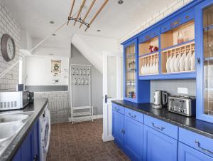 a kitchen with blue cabinets and a sink at Trewan Cottage in Holyhead