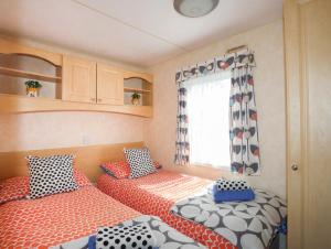 a caravan bedroom with two beds and a window at Trewan Chalet in Holyhead