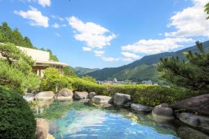 a pool of water with rocks and trees at Yunoshimakan in Gero