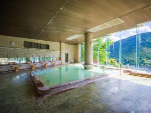 a swimming pool in a building with a mountain view at Yunoshimakan in Gero