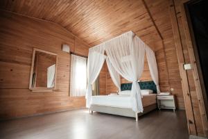 ein Schlafzimmer mit einem Himmelbett in einem Holzzimmer in der Unterkunft Serenity Bungalows in Cıralı