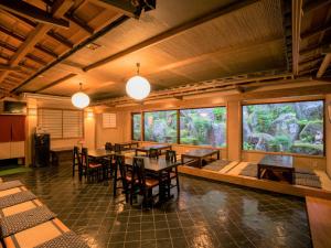 a dining room with tables and chairs and windows at Yunoshimakan in Gero