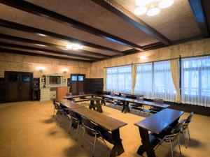 a large room with tables and chairs and windows at Yunoshimakan in Gero