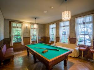 a pool table in a living room with windows at Yunoshimakan in Gero