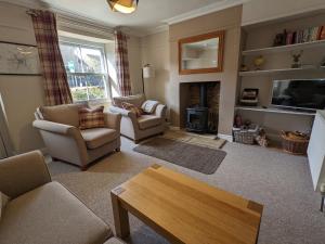 a living room with two chairs and a fireplace at The Cottage in Tetbury