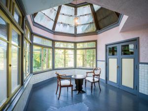 a conservatory with a table and chairs in a room with windows at Yunoshimakan in Gero
