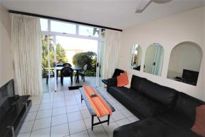 a living room with a black couch and a table at Mallorca 13 Duplex in Umdloti