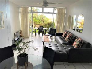 a living room with a black couch and a table at Mallorca 13 Duplex in Umdloti