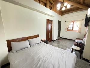 a bedroom with a large white bed and a desk at 芹壁山城民宿 Chinbe Hill Village House B&B in Beigan