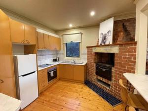 a kitchen with a white refrigerator and a brick fireplace at Ocean Road Holiday House in Marengo