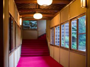a hallway with a pink carpet and windows at Yunoshimakan in Gero