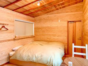 a bedroom with a bed in a wooden room at Yatsugatake Little Village Hotel in Hara