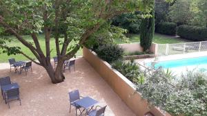 um pátio com piscina, cadeiras e uma árvore em Le Mas des Vergers em Salon-de-Provence