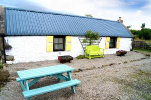 uma casa com uma mesa de piquenique azul em frente em Deveron Valley Cottages em Marnoch