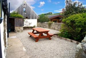 uma mesa de piquenique de madeira sentada sobre cascalho num jardim em Deveron Valley Cottages em Marnoch