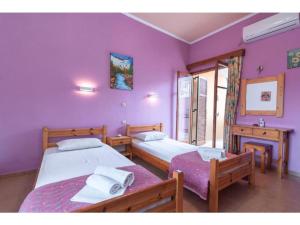2 Betten in einem Zimmer mit lila Wänden in der Unterkunft Steki Studio 2 in Benitses