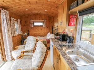 uma cozinha com cadeiras e um lavatório numa pequena casa em Shepherds Retreat em Kidderminster