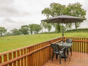 a table and chairs with an umbrella on a deck at Shepherds Retreat in Kidderminster