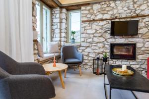 un soggiorno con un muro in pietra con una tv di Ahirona a Theológos