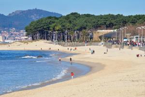 un grupo de personas caminando por la playa en Apartamento en Samil, en Vigo