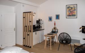 ein Zimmer mit einem kleinen Tisch und einer Küche mit einer Theke in der Unterkunft La Foulonnière de Neuville in Neuville-sur-Saône