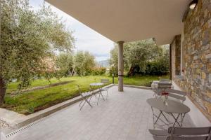 un patio con mesas y sillas y una pared de piedra. en Gli Ulivi Rooms And Breakfast, en Andora
