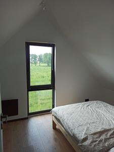 a bedroom with a bed and a large window at Czarny Domek Mazury in Pozezdrze