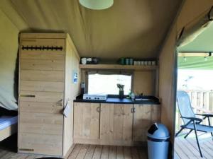 a small kitchen in a tiny house with a window at Minicamping de Vrolijke Flierefluiter in Someren-Heide