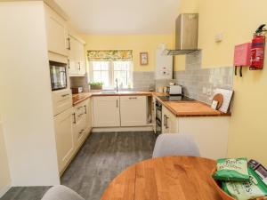 a kitchen with white cabinets and a wooden table at Kizzie Cottage in Morpeth