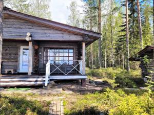 a log cabin with a porch in the woods at Lakeland Karelia Fisherman's Paradise in Kesälahti