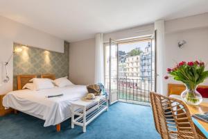 a bedroom with a bed and a balcony at Hôtel De La Vallée in Dinard