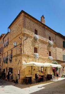 a building with tables and umbrellas in front of it at Residenza d'Epoca La Rosa in Pienza