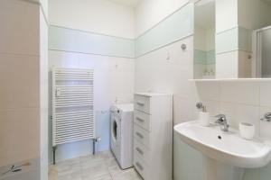 een witte badkamer met een wastafel en een wasmachine bij Pilsner Apartments in Pilsen