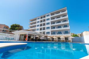 un hotel con piscina frente a un edificio en Apartaments La Perla Negra, en Cala Ratjada