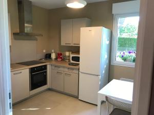 a kitchen with a refrigerator and a table and a window at Gite des 2 chênes entre Avenue verte, Lacs, Piscine et Casino in Forges-les-Eaux