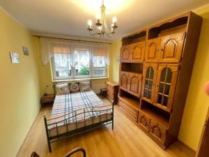 1 dormitorio con 1 cama y un gran armario de madera en YOURAPART Straganiarska z parkingiem en Gdansk