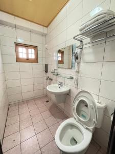 a white bathroom with a toilet and a sink at 芹壁山城民宿 Chinbe Hill Village House B&B in Beigan