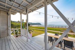 - une terrasse couverte avec une table et des chaises et l'océan dans l'établissement SHIRAHAMA BEACH GARDEN, à Miyazaki