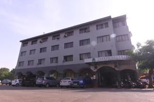 伯杰默里Hotel Indraprastha pachmarhi的一座白色的大建筑,前面有汽车停放