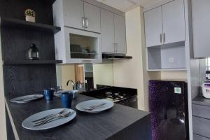 - une cuisine avec une table, des assiettes et des ustensiles dans l'établissement Apt Pejaten Park Residence 2 BR Grey dgn Netflix, Bathub, Pool, à Jakarta