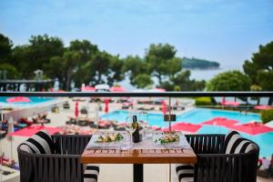 a table with a glass of wine next to a pool at Hotel Parentium Plava Laguna in Poreč