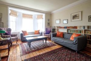 a living room with a couch and chairs and bookshelves at Beach House - Aldeburgh Coastal Cottages in Aldeburgh