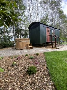 ein kleines grünes und schwarzes Haus mit einer Holzbadewanne in der Unterkunft Heywood Glamping in Ormskirk