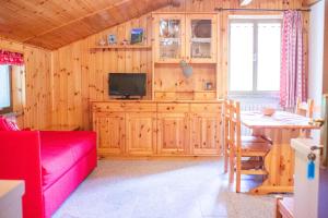 a living room with a red couch and a television at La Piana Appartamenti in Alpe Devero