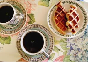 a table with two cups of coffee and a plate of waffles at Mayfair Rodemtree Pension in Pyeongchang