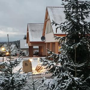 a house in the snow with a sign in front of it at Domek Dzika Konwalia 2 in Zieleniec
