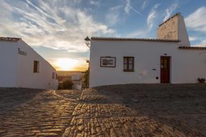 un edificio blanco con la puesta de sol en el fondo en A Janela Do Castelo, en Monsaraz