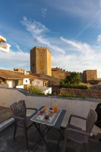 una mesa y sillas en un balcón con un castillo en A Janela Do Castelo, en Monsaraz