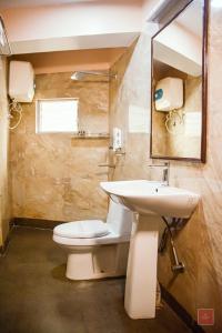 bagno con lavandino, servizi igienici e specchio di Zambala Retreat & Spa Darjeeling a Darjeeling